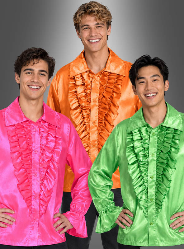 Drei Männer stehen lächelnd da; jeder trägt ein glänzendes Retro-70er-Rüschenhemd im Schlagerstar-Stil aus rosa, orangefarbenem und grünem Satin – im klassischen Retro-Stil der 70er Jahre – vor einem grauen Hintergrund mit Farbverlauf.