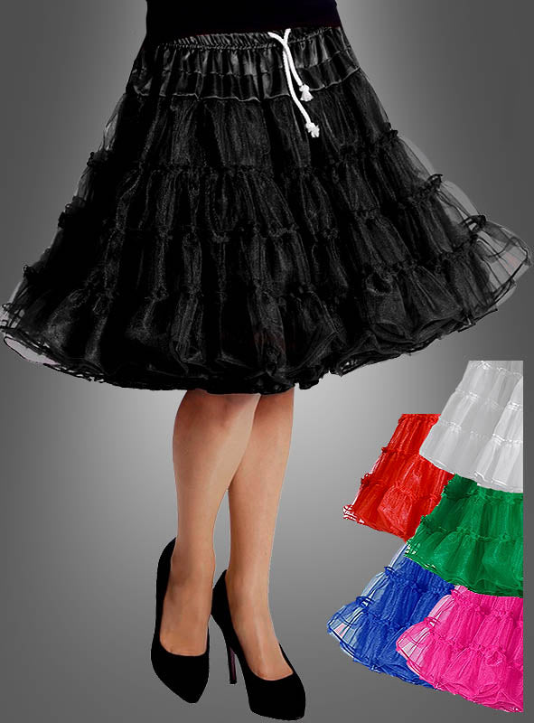 Eine Person trägt den „Luxus Petticoat Rock“ mit extra Volumen in Schwarz, der sich durch bezaubernde Rüschen und einen weißen Kordelzug auszeichnet und stilvoll mit schwarzen Pumps kombiniert wird. Ganz im Stil der Mode der 50er Jahre ist der Rock außerdem in den Farben Weiß, Rot, Grün, Blau und Rosa erhältlich.