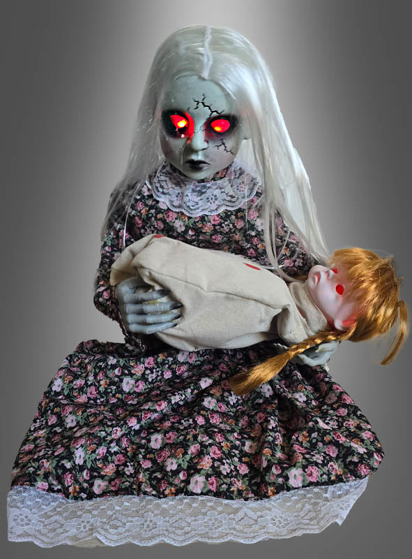 Das animierte Zombie-Mädchen mit der weinenden Puppe besticht durch rissige, graue Haut, leuchtend rote Augen und langes weißes Haar. Es hält eine weitere Puppe in einem Kleid mit Blumenmuster vor einem grauen Hintergrund – die perfekte Halloween-Dekoration für eine gruselige Atmosphäre.