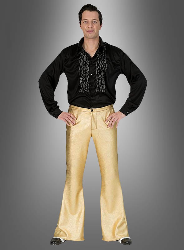 Ein Mann steht mit den Händen in den Hüften da, gekleidet in ein schwarzes Rüschenhemd und eine glänzende, goldene Disco-Schlaghose im Stil der 70er Jahre, und verkörpert vor einem grauen Hintergrund mit Farbverlauf das authentische Flair der 70er Jahre.