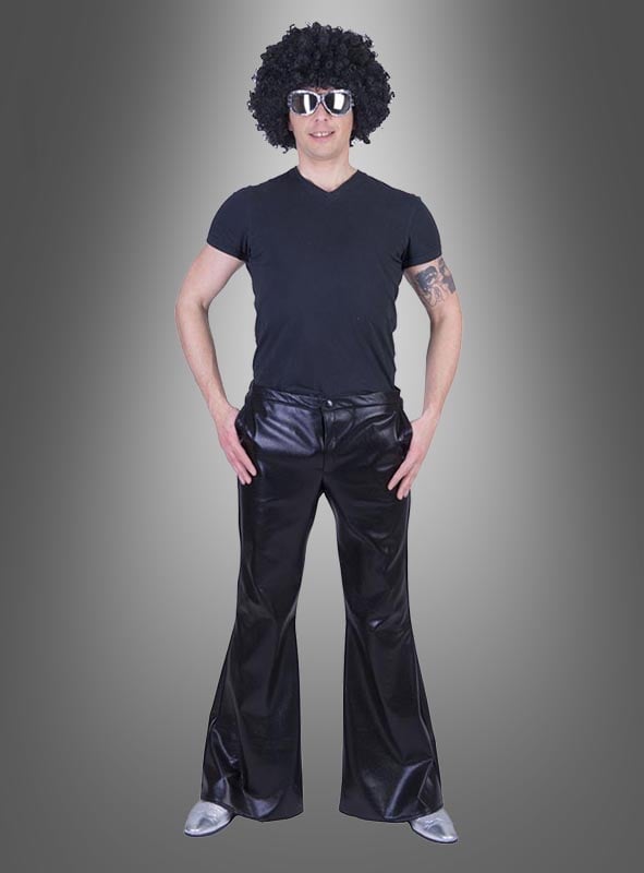 Eine Person mit schwarzer Perücke, Sonnenbrille, schwarzem T-Shirt, glänzender Disco-Schlaghose im Stil der 70er Jahre und silbernen Schuhen steht vor einem grauen Hintergrund mit Farbverlauf – perfekt für jede Karnevals- oder 70er-Jahre-Mottoparty.