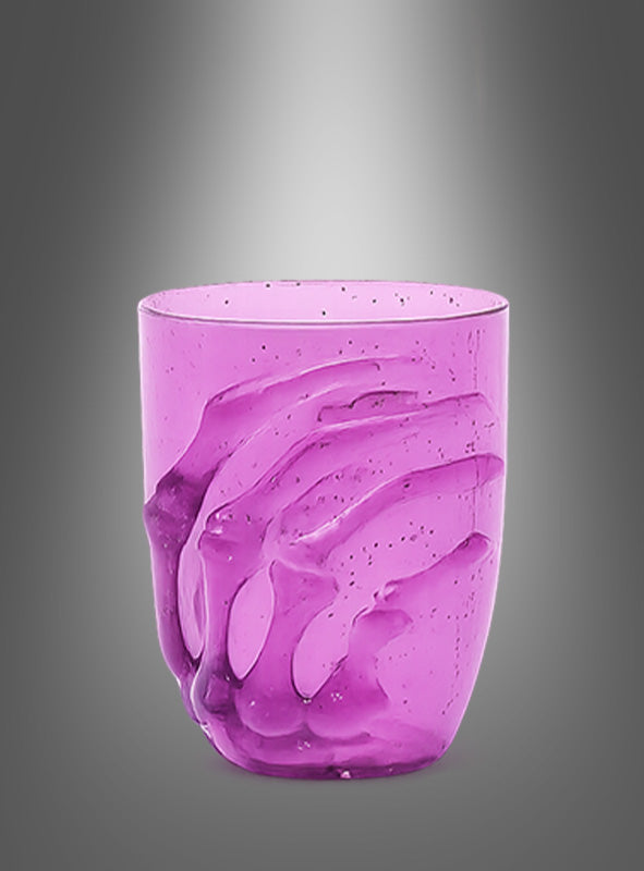 Ein durchscheinendes, violettes „Halloween-Glas 10 cm mit Skelett-Hand“ ist an der Seite mit einem erhabenen Skelett-Hand-Motiv verziert, das sich um die Seite windet, und eignet sich somit ideal als gruseliges Halloween-Glas für die Tischdekoration, präsentiert vor einem grau abgestuften Hintergrund.