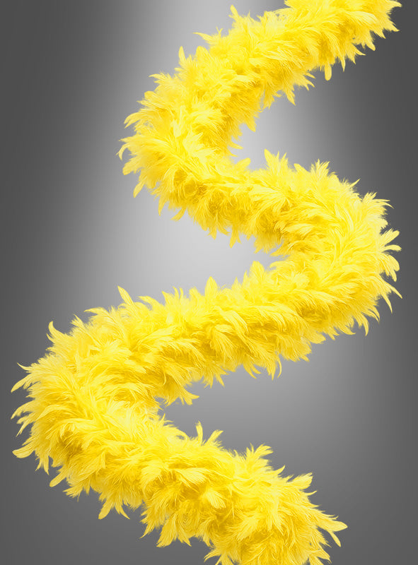 Das Federboa „20er Jahre“ (180 cm) in leuchtendem Gelb ist in einer lockeren Spirale vor einem grauen Hintergrund mit Farbverlauf dargestellt.