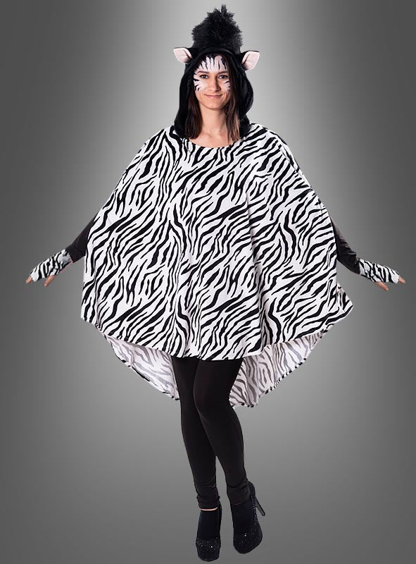 Ein Model trägt den Plüsch-Zebra-Poncho in den Größen XS–XXXL mit auffälligen schwarz-weißen Streifen, dazu einen Kopfschmuck mit Zebra-Ohren, Gesichtsbemalung und schwarze Leggings; es steht mit leicht ausgestreckten Armen vor einem grauen Hintergrund.