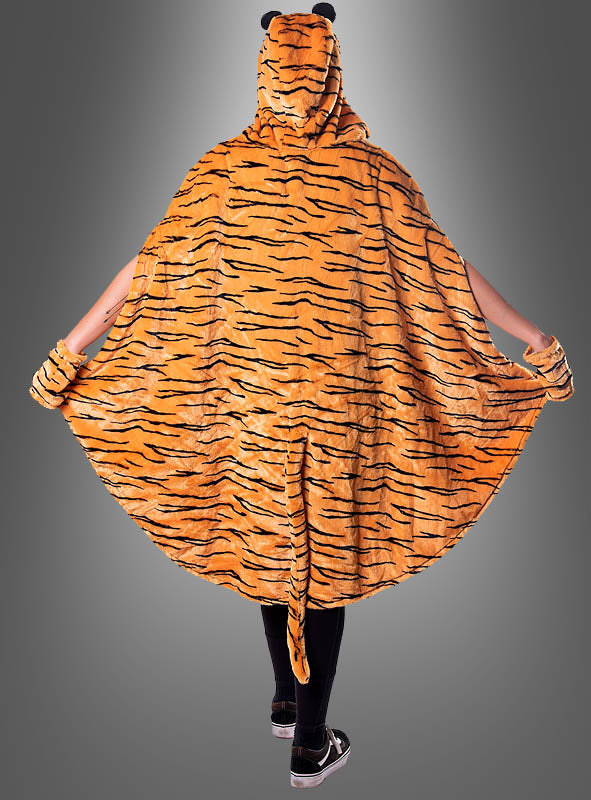 Eine Person steht mit ausgestreckten Armen da und trägt den „Tiger-Poncho aus hochwertigem Plüsch S-XXXL“– ein auffälliger, orange-schwarz gestreifter Kapuzenumhang mit passenden Bündchen und einem Schwanz –, der sich ideal für Ihr nächstes Gruppenkostüm zum Karneval eignet, vor einem grauen Hintergrund.