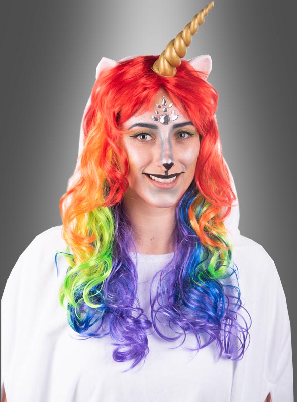 Vor einem grauen Hintergrund ist eine Person zu sehen, die ein Einhorn-Karnevalskostüm trägt, bestehend aus einem goldenen Horn, einer roten Perücke mit Regenbogenfarben, Gesichtsbemalung und dem „Wandelbaren weißen Poncho aus Plüsch S-XXXL“.
