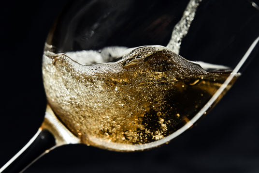 Nahaufnahme eines sprudelnden Getränks, das in ein Glas gegossen wird, wobei Bläschen und Schaum vor schwarzem Hintergrund zu sehen sind.