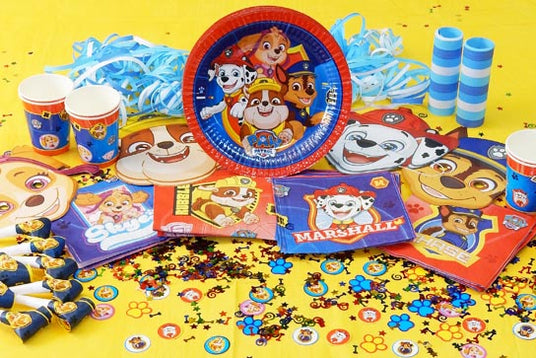 Partyzubehör zum Thema „Paw Patrol“, darunter Teller, Becher, Servietten, Trillerpfeifen, Dekorationen und Konfetti, präsentiert auf einem gelben Hintergrund.