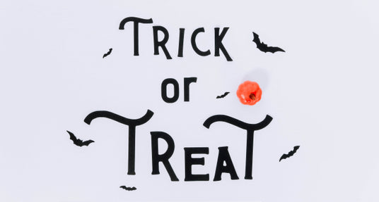 Die Worte „Trick or Treat“ sind in schwarzen Buchstaben geschrieben, dazu gibt es kleine schwarze Fledermaus-Illustrationen und einen orangefarbenen Kürbis auf weißem Hintergrund.