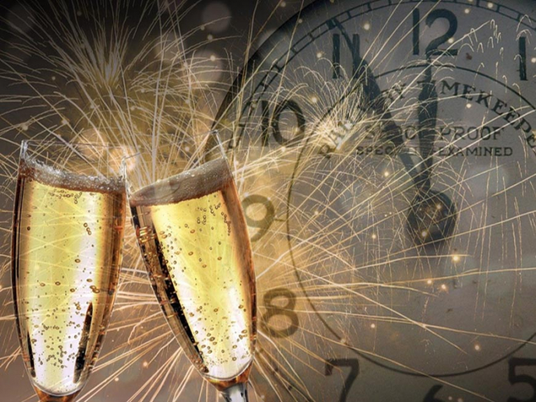 Vor dem Hintergrund eines Feuerwerks und einer Nahaufnahme einer Uhr, die Mitternacht anzeigt, stoßen zwei Champagnergläser aneinander.