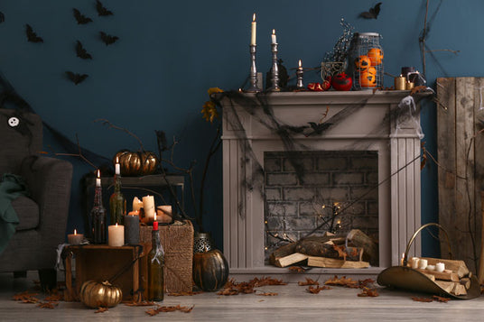 Ein Wohnzimmer im Halloween-Stil mit einem geschmückten Kamin, Kerzen, Kürbissen, Spinnweben, Fledermäusen an der Wand, Herbstblättern und Gläsern auf dem Kaminsims.