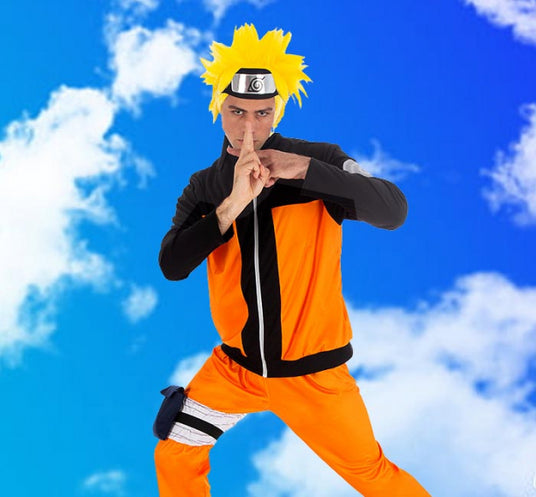 Eine Person in einem orange-schwarzen Anime-Kostüm posiert mit den Händen in einer Ninja-Geste vor einem strahlend blauen Himmel mit weißen Wolken.