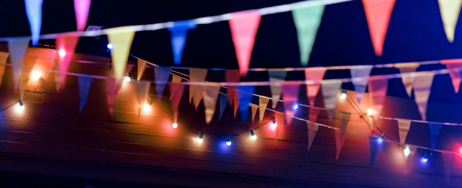 Nachts werden bunte dreieckige Wimpel und Lichterketten über den Köpfen aufgehängt, was vor dem dunklen Hintergrund eine festliche Atmosphäre schafft.