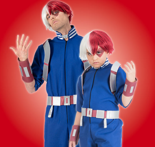 Zwei Personen, die identische blaue Overalls, rot-weiße Perücken und Gürtel tragen, posieren vor einem roten Hintergrund.