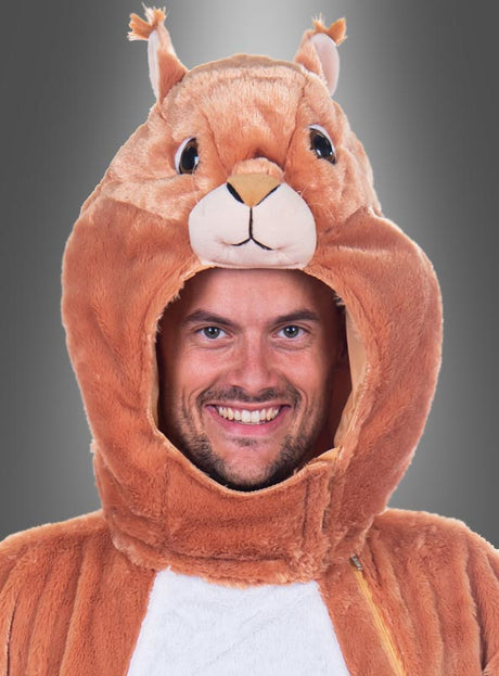 Ein Mann, der lächelt, während er eine waschbare Plüsch-Eichhörnchen-Maske mit Schwanz trägt, wobei die Maske über seinem Kopf sitzt, vor einem Hintergrund mit Farbverlauf.