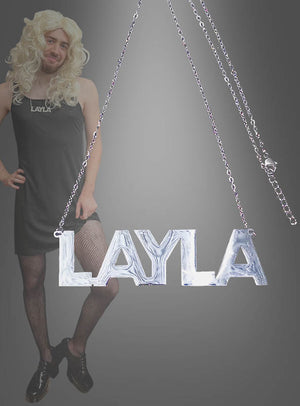 Eine Person in einem schwarzen Kleid, Netzstrümpfen und einer blonden Perücke posiert neben der protzigen „Layla Kette silber Namenskette 9,5 cm“ – einer auffälligen silbernen Namenskette mit dem Namen LAYLA, die sich perfekt als Accessoire für eine Malle-Party eignet.