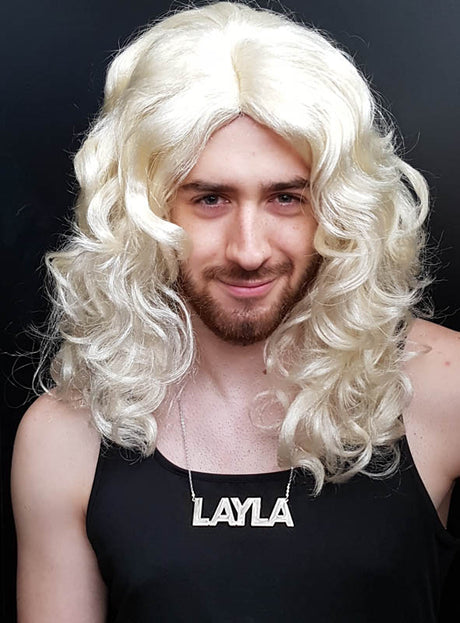 Die Person trägt eine lange, lockige blonde Perücke und ein schwarzes Trägertop und präsentiert die auffällige „Layla Kette“ – eine silberne Namenskette (9,5 cm) mit der Aufschrift „LAYLA“ vor einem schlichten dunklen Hintergrund –, die sich ideal als verspieltes Accessoire für eine Malle-Party eignet.