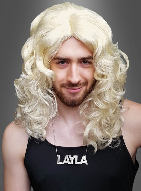 Eine Person mit Bart trägt vor einem grauen Hintergrund das „Layla Set“ – bestehend aus einer langen, lockigen blonden Perücke und einer Halskette – sowie ein schwarzes Tanktop.