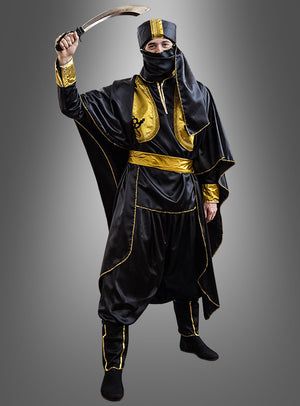 Eine Person, die das Tuareg-Orientkostüm „Ölscheich 1001 Nacht“ in Schwarz und Gold trägt, hält ein Krummschwert über den Kopf, während sie eine dazu passende Kopfbedeckung und Maske trägt und vor einem grauen Hintergrund mit Farbverlauf steht.