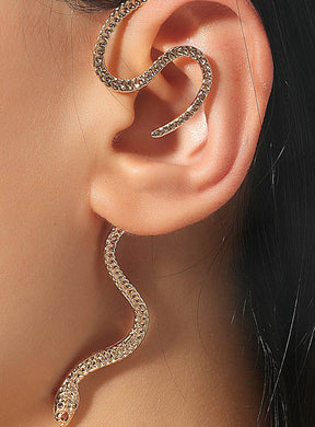 Ein goldener Schlangen-Ohrschmuck schlängelt sich elegant am äußeren Rand des Ohrs entlang, wobei der Kopf der Schlange unter dem Ohrläppchen hängt und sich ihr Schwanz über das Ohr krümmt – ein auffälliges Schmuckstück aus einer goldenen Modeschmuckkollektion, das jedem Look einen besonderen Akzent verleiht.