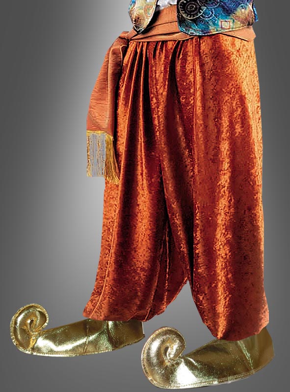 Person, die eine weite, orangefarbene Samthose mit einer Schärpe und goldene „Wüstenprinz“-Schnabelschuh-Überzieher mit nach oben gebogenen Zehen trägt, die an „1001 Nacht“ erinnern. Der Oberkörper ist teilweise zu sehen. Neutraler Hintergrund mit Farbverlauf.