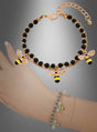 Der „Bienen Armband Kostümschmuck“ besteht aus einem goldenen Armband mit schwarzen Perlen und zwei Bienen-Anhängern, die Ihrem Look eine verspielte Note verleihen. Vor einem Farbverlaufshintergrund präsentiert und elegant am Handgelenk in Szene gesetzt, eignet sich dieses zarte Bettelarmband perfekt für jeden Anlass.