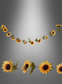 Zwei „Deko Sonnenblumen“-Girlanden (220 cm) mit grünen Blättern sind vor einem grau abgestuften Hintergrund abgebildet, wobei eine Girlande geschwungen und die andere gerade angeordnet ist. Diese festlichen Girlanden bestehen aus naturgetreuen Kunstblumen und sorgen für eine bezaubernde dekorative Note.