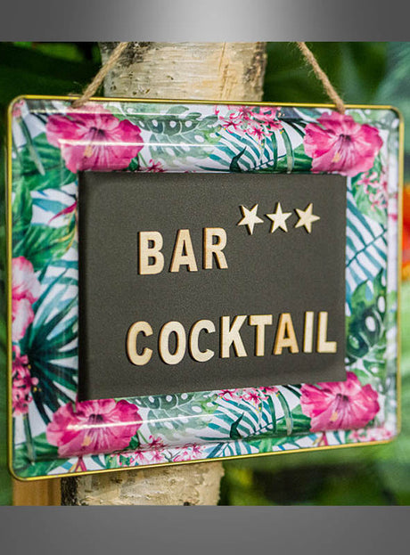 An einem Baum hängt eine Metalltafel mit tropischen Blumen, deren blumiger Rahmen die Schriftzug „BAR *** COCKTAIL“ in Holzbuchstaben vor schwarzem Hintergrund hervorhebt – ein echter Blickfang für Ihre Hawaii-Partydekoration.