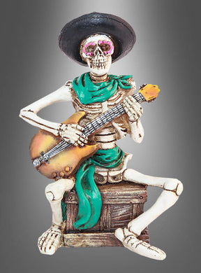 Skelettfigur „Mexikaner mit Gitarre“, 15 cm – eine Skelettfigur mit schwarzem Hut und grünem Schal, die auf einer Kiste sitzt und vor einem grauen Hintergrund mit Farbverlauf Akustikgitarre spielt. Perfekt als einzigartige „Day of the Dead“-Figur oder für deine „Tag der Toten“-Dekofigurensammlung!.