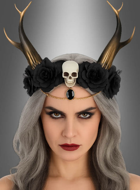 Eine Frau mit langen grauen Haaren trägt das Blumen-Haarband „Dämonin mit Hörnern“, ein Gothic-Haarband mit schwarzen Blumen, Hörnern, einem Totenkopf und einem schwarzen Edelstein. Mit ihrem auffälligen Make-up und ihrem ernsten Gesichtsausdruck vor grauem Hintergrund verkörpert sie einen ätherischen und zugleich kraftvollen Look – damit ist dies das perfekte Halloween-Accessoire für alle, die auf der Suche nach dramatischem Flair sind.