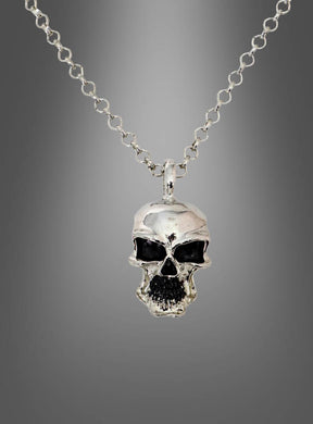 Die „Totenkopf Biker Pirat Kette silber aus Metall“ ist eine silberne Halskette mit einem metallischen Totenkopf-Anhänger, dessen Augen und Mund mit schwarzen Akzenten versehen sind, was sie zu einem idealen Halloween-Schmuckstück macht. Die elegante silberne Halskette wird vor einem grauen Hintergrund mit Farbverlauf präsentiert.