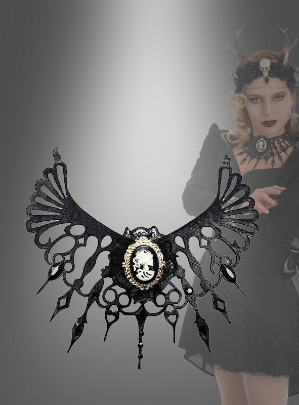 Gothic Collier – Halsschmuck mit Brosche, verziert mit kunstvollen Ausschnitten und einem zentralen Kameo-Anhänger; im unscharfen Hintergrund ist eine Frau in dunkler Kleidung zu sehen, die passenden Gothic-Schmuck trägt.