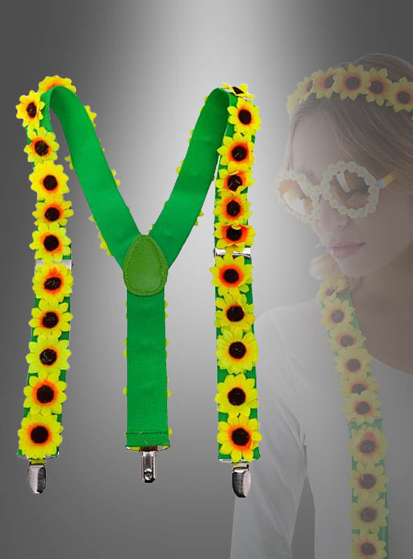 Die „Sonnenblumen-Hosenträger“ – grüne Hosenträger, verziert mit gelben Kunstsonnenblumen – werden zusammen mit einem passenden Stirnband und einer Brille geliefert, wie sie die Frau im Hintergrund trägt. Dieses Set ist das perfekte „Sonnenblumen-Kostüm“ oder ein farbenfrohes Hippie-Accessoire für Ihre nächste Mottoparty.