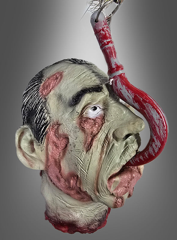 Eine realistische Halloween-Dekoration: Ein Horror-Kopf mit Zunge und verwesender Haut, der auf grausame Weise mit einem großen, blutverschmierten Fleischhaken durch den Mund aufgespießt ist – vor einem grauen Hintergrund mit Farbverlauf. Perfekt als auffällige Dekoration für eine Zombie-Party oder als unvergesslicher Blickfang auf dem Tisch.