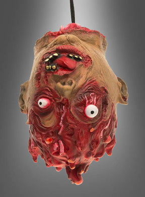 Eine bis ins grausame Detail ausgearbeitete Latex-Requisite in Form eines abgetrennten Zombie-Kopfes mit hervorquellenden Augen, freiliegenden Zähnen und blutigem, verwesendem Fleisch hängt kopfüber vor einem grauen Hintergrund mit Farbverlauf – perfekt für Ihre Halloween-Dekoration.