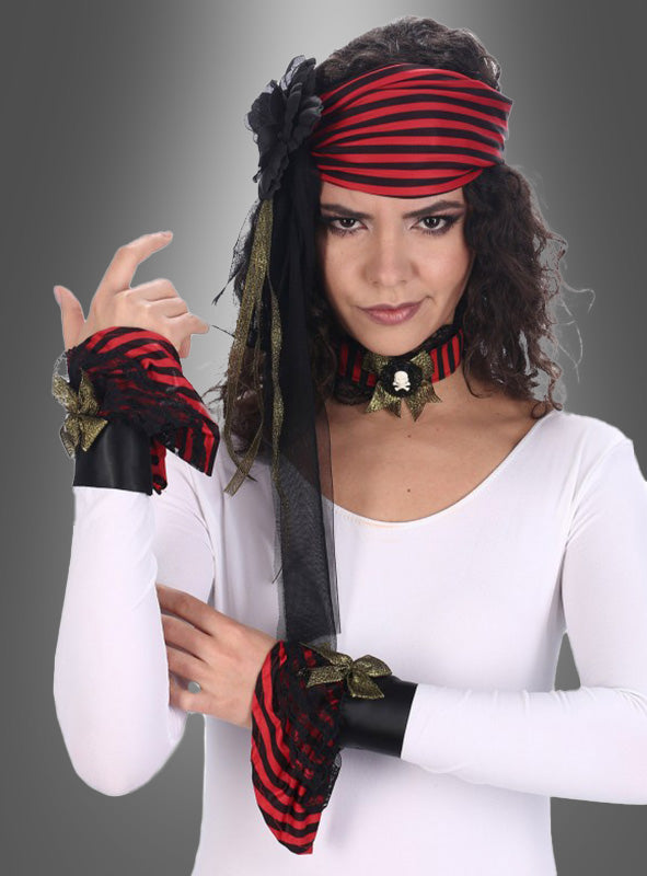 Eine Frau, die das gestreifte „Piratin“-Accessoire-Set trägt – bestehend aus einem rot-schwarz gestreiften Stirnband, passenden Armbändern und einem Halsband –, posiert in einem weißen Oberteil vor einem grauen Hintergrund, bereit für ihr Karnevalskostüm.