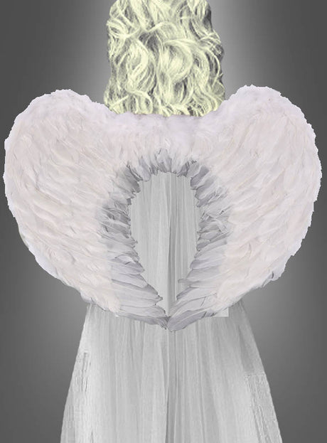 Eine Person mit langen, lockigen blonden Haaren trägt ein weißes Kleid und große weiße Engelsflügel, die beidseitig mit Federn verziert sind (60 cm), und steht vor einem grauen Hintergrund mit Farbverlauf.