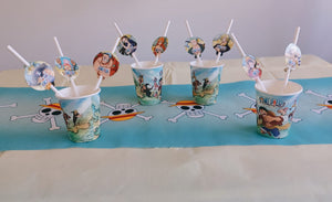 Fünf „One Piece“-Pappbecher (250 ml) mit Strohhalmen stehen auf einem Tisch – perfekt für jede Anime-Party oder jeden Kindergeburtstag. Der Tisch ist mit einem blauen Tischläufer verziert, auf dem Piratentotenköpfe und gekreuzte Knochen aus „One Piece“ abgebildet sind, was für eine abenteuerliche Atmosphäre sorgt.