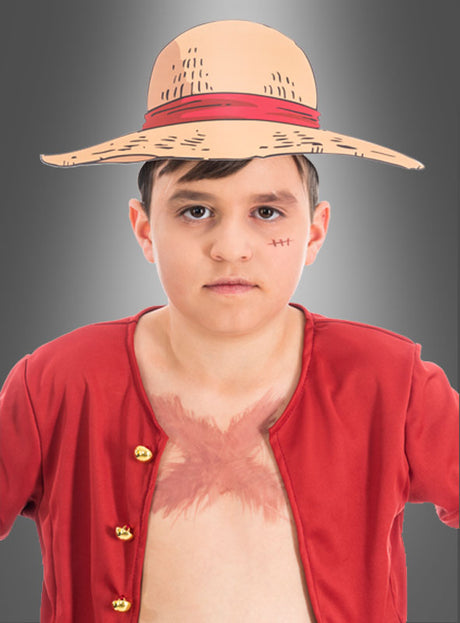 Ein Junge mit Strohhut, rotem, offenem Hemd und einer Narbe auf der Brust, verkleidet als Strohhut-Ruffy aus „One Piece“, steht vor einem grauen Hintergrund – die perfekte Inspiration für einen „One Piece“-Kindergeburtstag oder alle, die auf der Suche nach einzigartigen „One Piece“-Papierkopfbedeckungen sind.