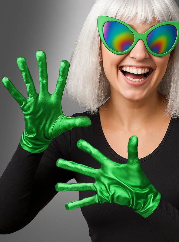 Eine Person mit weißem Haar trägt eine Regenbogen-Cat-Eye-Sonnenbrille, ein schwarzes Shirt und „Grüne Alien-Handschuhe“ mit glänzenden, länglichen Fingern – ein außerirdisches Alien-Kostüm-Accessoire –, während sie lächelnd und verspielt vor einem grauen Hintergrund posiert.
