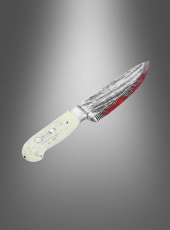 Ein gezacktes „Blutiges Küchenmesser“ (33 cm) mit einem abgenutzten, hellen Griff und einer teilweise rot befleckten Klinge wird vor einem grauen Hintergrund mit Farbverlauf präsentiert und ist damit die perfekte Ergänzung für jedes Horror-Kostüm oder ein gruseliges Horror-Accessoire.