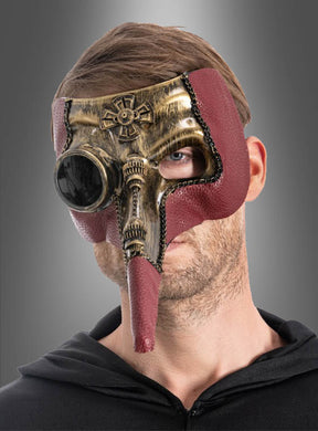 Ein Mann, der die „Steampunk Pestdoktor“-Maske trägt – eine Halbmaske mit bronzefarbenen Metallic- und roten Akzenten, die sich durch eine lange Nase und runde Augenöffnungen auszeichnet –, steht vor einem grauen Hintergrund.