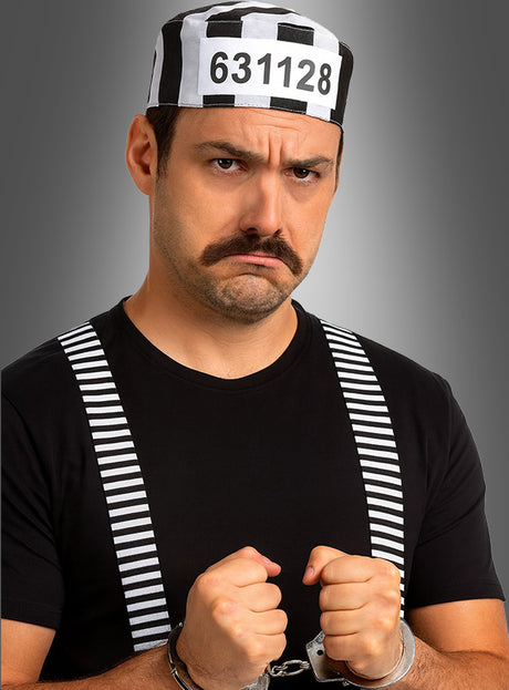 Ein Mann in einem schwarz-weiß gestreiften Outfit aus dem Set „Sträfling – Gefangene 3-tlg.“, der Handschellen trägt und vor einem grauen Hintergrund verstört wirkt – das perfekte Karnevalsaccessoire oder ein auffälliges Kostüm.