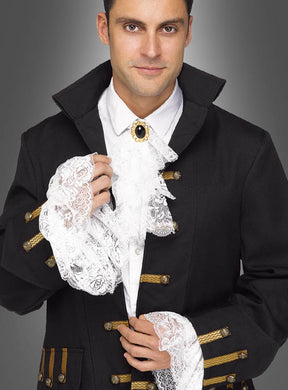 Vor einem grauen Hintergrund steht ein Mann, der eine schwarze historische Jacke mit goldener Borte trägt, ergänzt durch die „Barock Manschetten und Jabot aus Spitze“ mit weißen Spitzenmanschetten und einem Spitzenjabot.