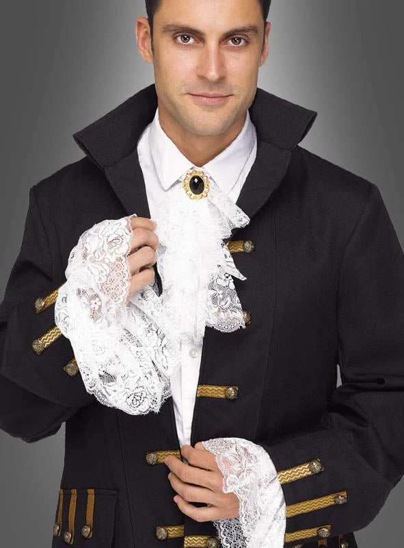 Vor einem grauen Hintergrund steht ein Mann, der eine schwarze historische Jacke mit goldener Borte trägt, ergänzt durch die „Barock Manschetten und Jabot aus Spitze“ mit weißen Spitzenmanschetten und einem Spitzenjabot.