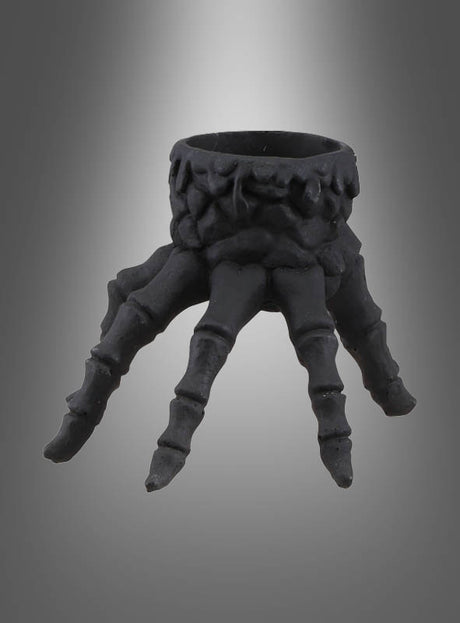 Skeletthand-Kerzenhalter aus Polyresin, 13 x 10 cm – ein schwarzer, ringförmiger Kerzenhalter, der wie eine knochige Skelethand mit vier nach unten ragenden Fingern gestaltet ist und vor einem grauen Hintergrund mit Farbverlauf steht – perfekt, um Ihrer Halloween-Dekoration eine gruselige Note zu verleihen oder als einzigartiges Deko-Element aus Polyresin.