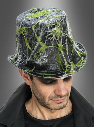 Ein Mann, der den „Verrotteter Moos Zylinder mit Spinnenweben“ trägt – einen schwarzen Halloween-Zylinder, der mit Moos und Spinnweben bedeckt ist –, mit dunklem Make-up um die Augen, der nach unten blickt.