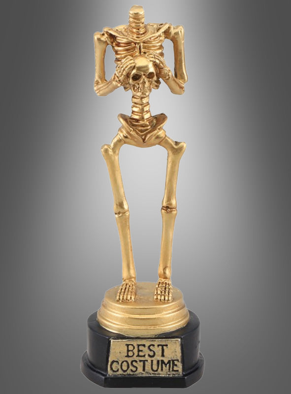 Eine „Goldene Skelett-Trophäe für das beste Halloween-Kostüm“ steht auf einem schwarzen Sockel mit der Aufschrift „Best Costume“ vor einem grauen Farbverlauf – die ideale Auszeichnung für jeden Gewinner des besten Halloween-Kostüms.