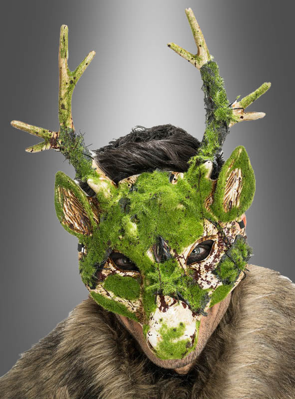 Eine Person, die eine grüne „Moos Effekt Reh Maske mit Geweih“ mit Moosstruktur und pelzige Kleidung trägt, vor einem grauen Hintergrund mit Farbverlauf.