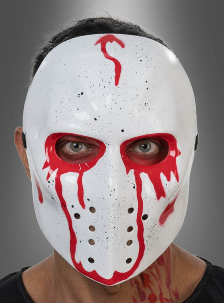 Eine Person, die die „Blutige Hockey-Maske Halloween“ trägt – eine weiße Hockeymaske mit roter, blutähnlicher Farbe, schwarzen Sprenkeln und sichtbaren Augenlöchern –, steht vor einem schlichten grauen Hintergrund, was sie zur idealen Wahl für Fans klassischer Horrorfilm-Masken-Designs macht.